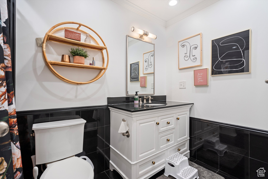Bathroom featuring tile walls, vanity, toilet, and ornamental molding