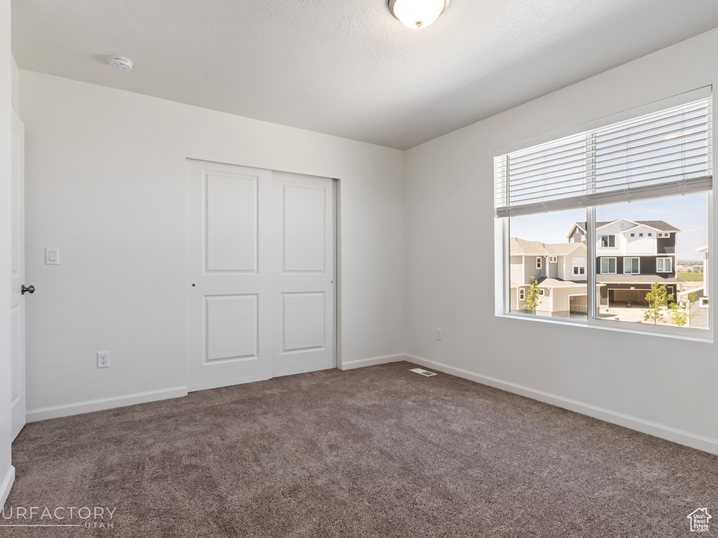 Unfurnished bedroom featuring a closet, carpet, and multiple windows