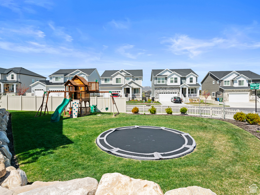 View of yard featuring a playground and a trampoline
