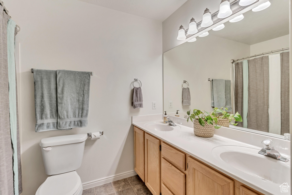 Bathroom featuring toilet, tile floors, and double sink vanity