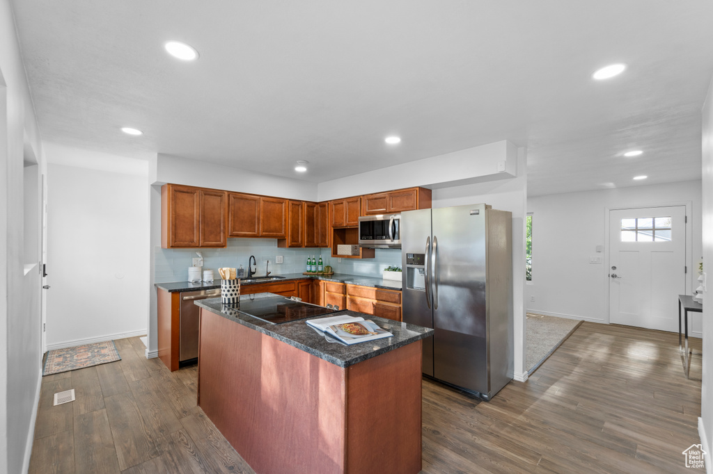 Kitchen with a center island, sink, stainless steel appliances, and hardwood / wood-style floors