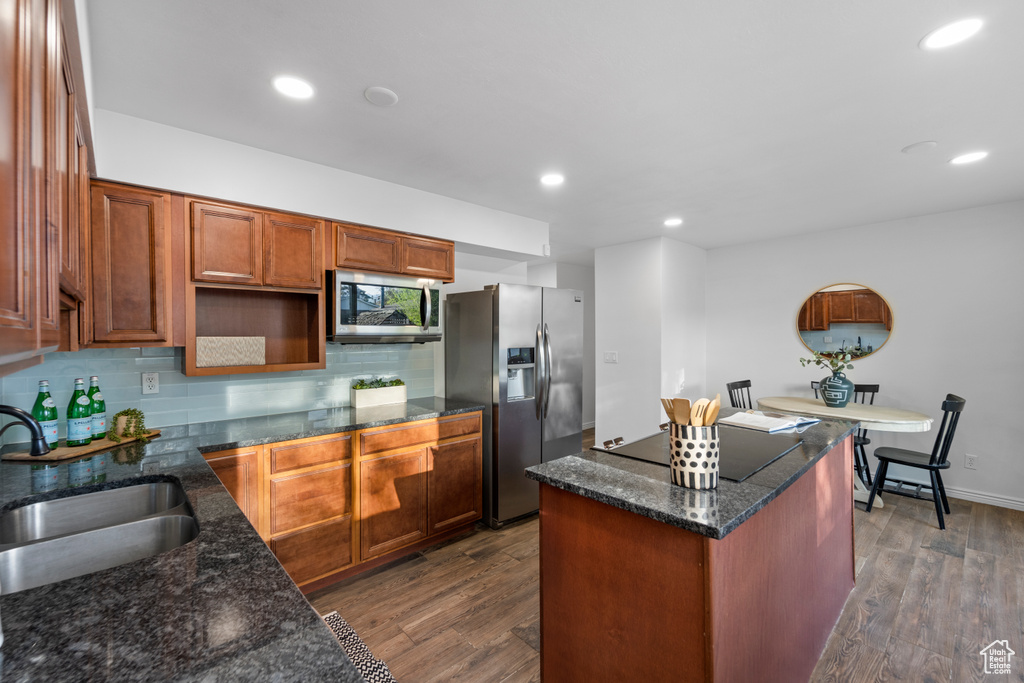 Kitchen featuring a center island, dark hardwood / wood-style flooring, stainless steel appliances, tasteful backsplash, and dark stone counters