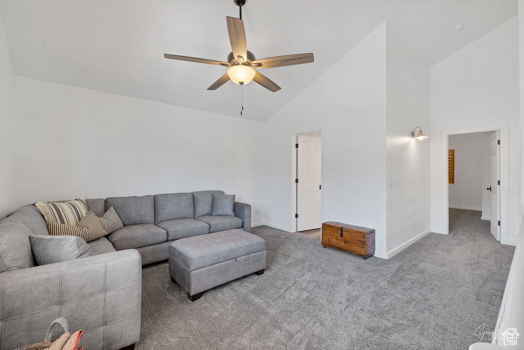 Living room featuring high vaulted ceiling, ceiling fan, and carpet
