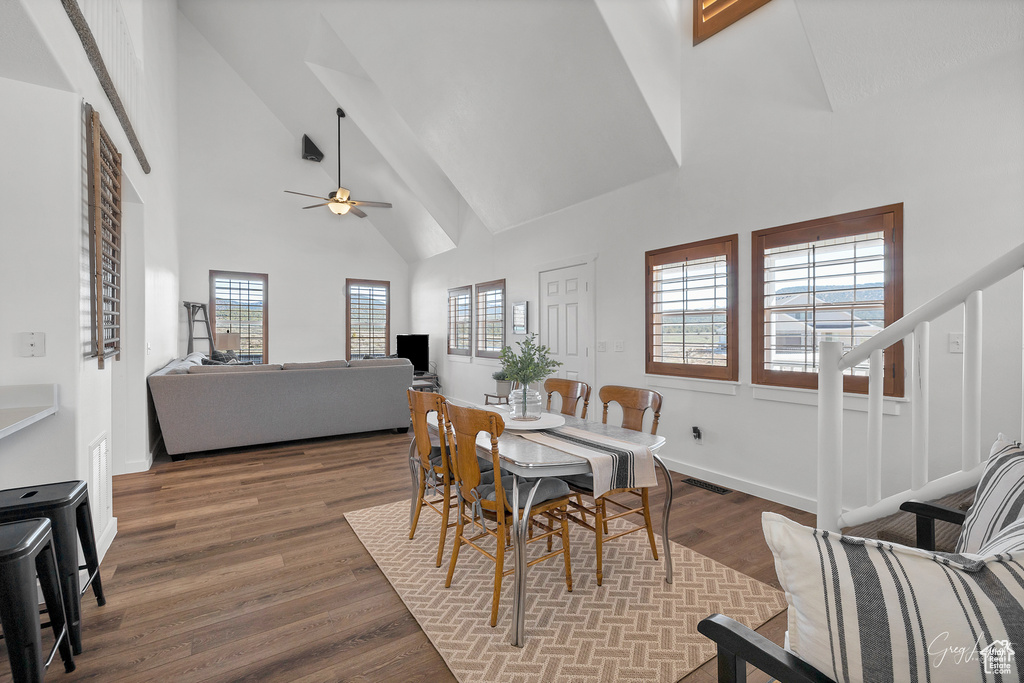 Dining space with hardwood / wood-style floors, high vaulted ceiling, and ceiling fan