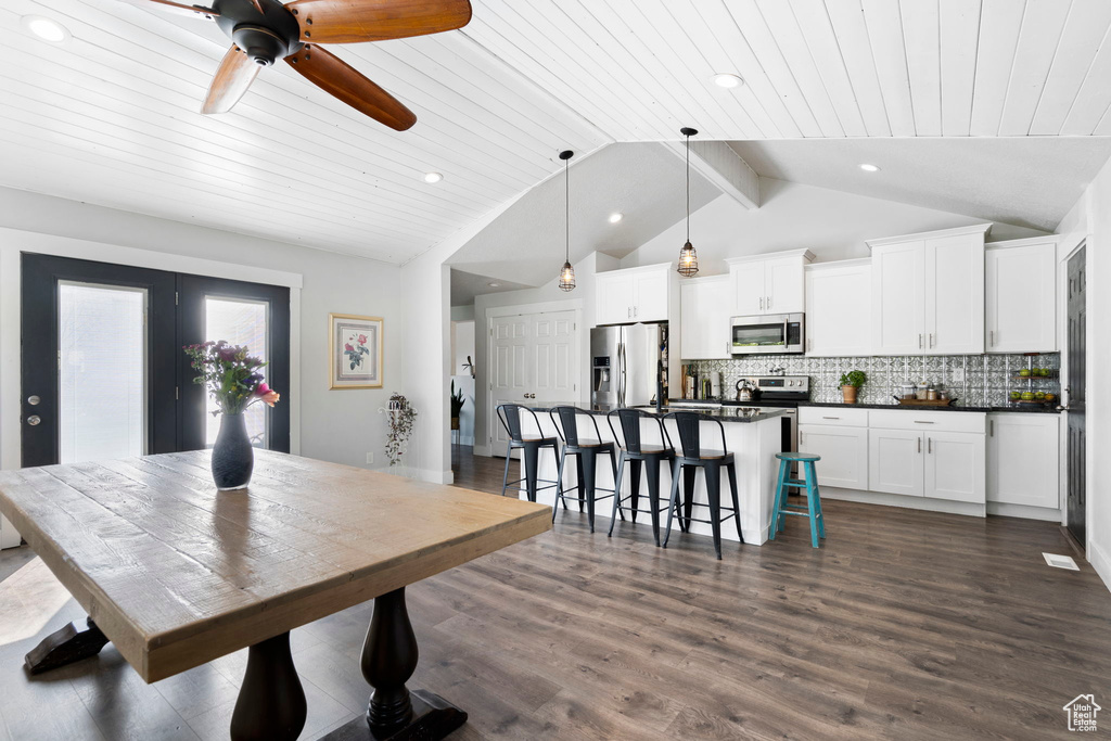 Dining room featuring ceiling fan, lofted ceiling with beams, and dark hardwood / wood-style flooring