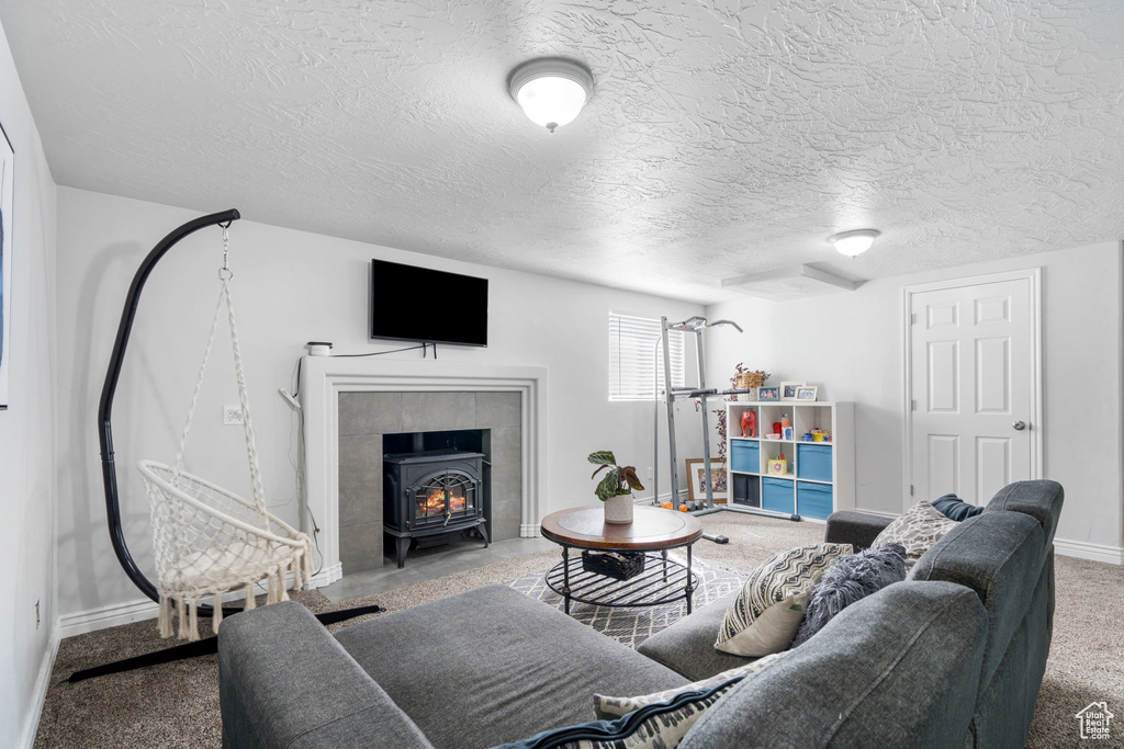 Living room with a wood stove, a tiled fireplace, and a textured ceiling