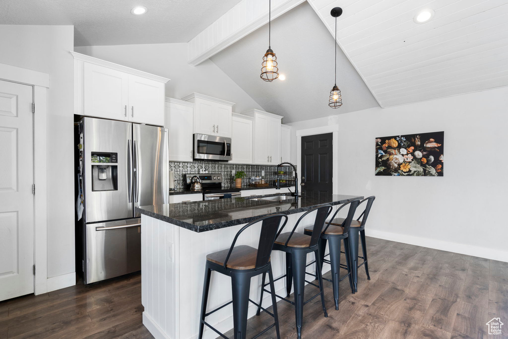 Kitchen with appliances with stainless steel finishes, sink, dark wood-type flooring, a center island with sink, and pendant lighting