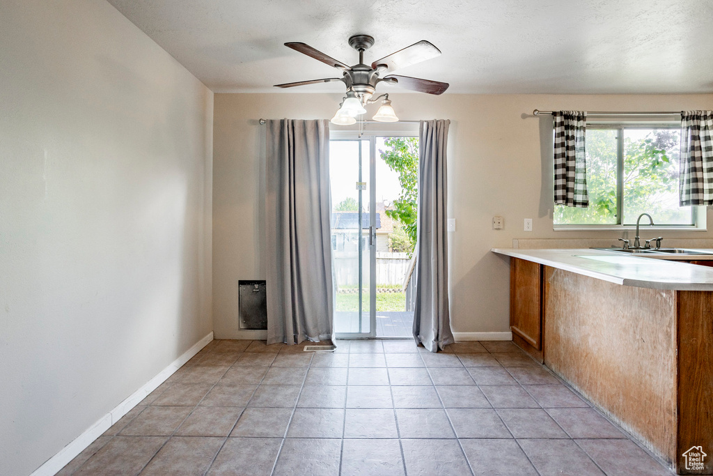 Interior space featuring plenty of natural light, sink, ceiling fan, and light tile flooring