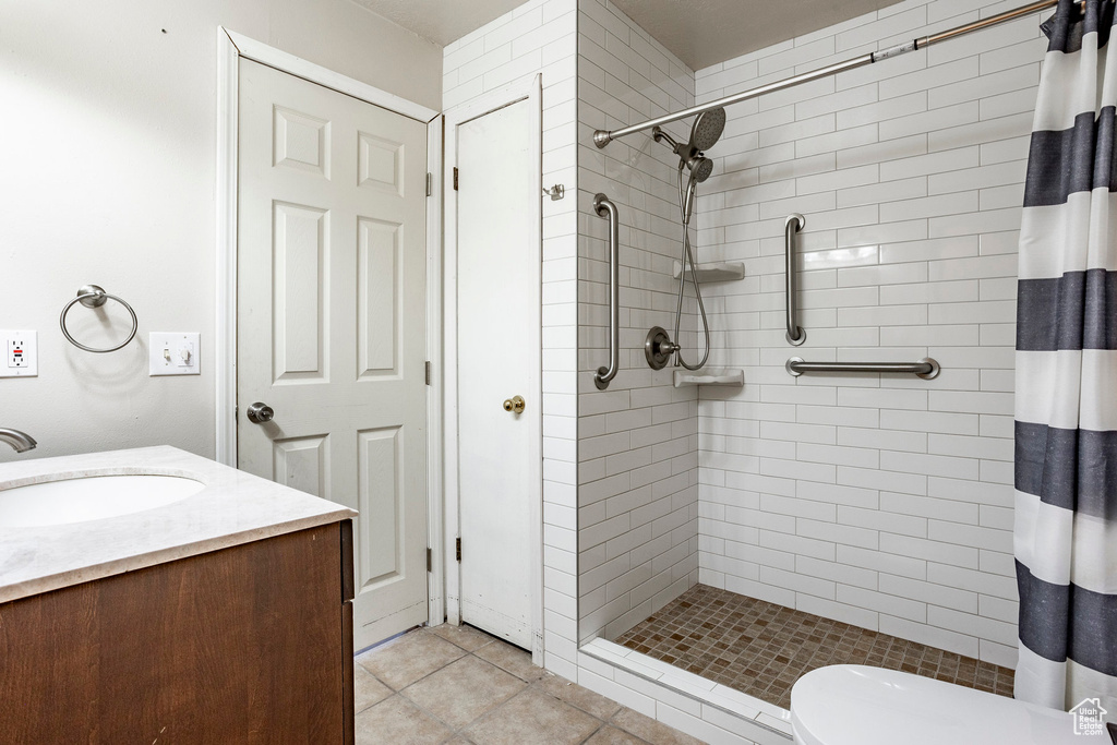 Bathroom featuring tile flooring, vanity, toilet, and a shower with curtain