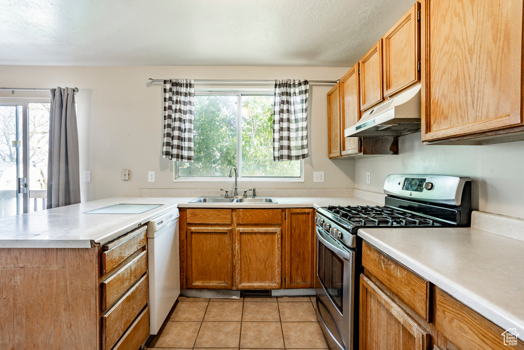 Kitchen with kitchen peninsula, stainless steel range with gas cooktop, light tile flooring, dishwasher, and sink