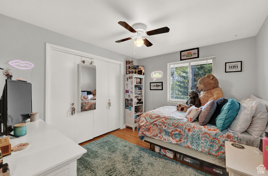 Bedroom with light hardwood / wood-style flooring, ceiling fan, and a closet