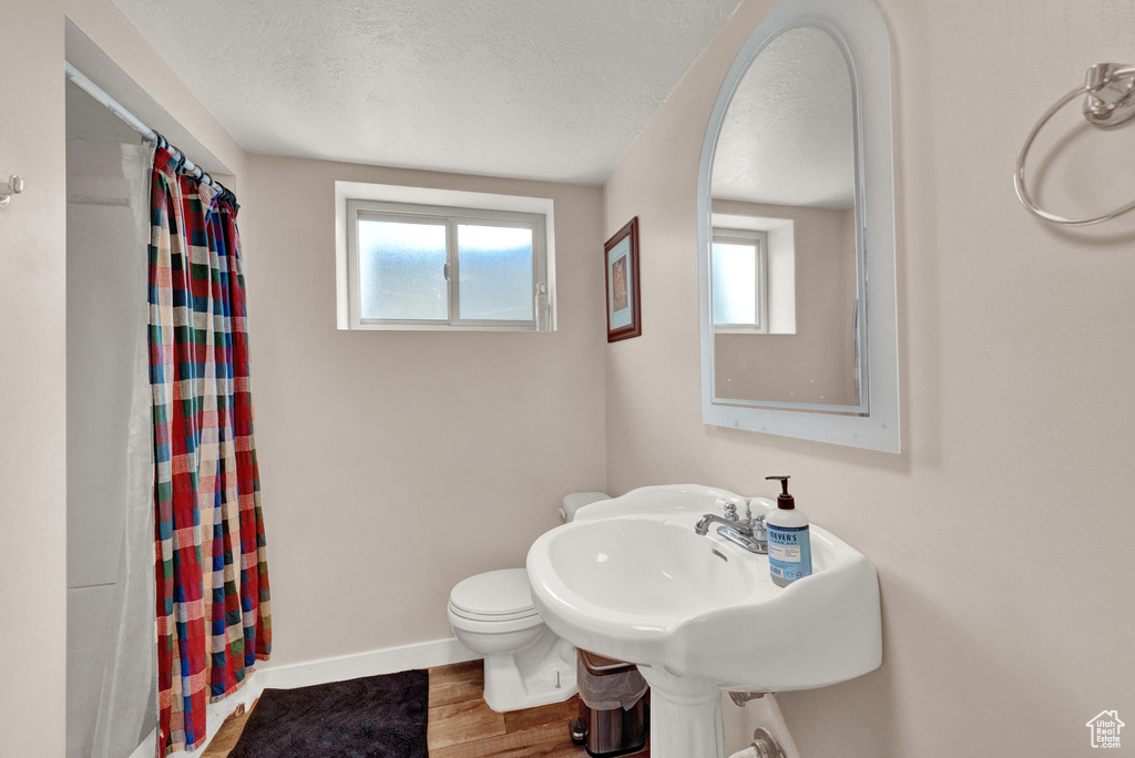Bathroom with a healthy amount of sunlight, hardwood / wood-style flooring, toilet, and a textured ceiling