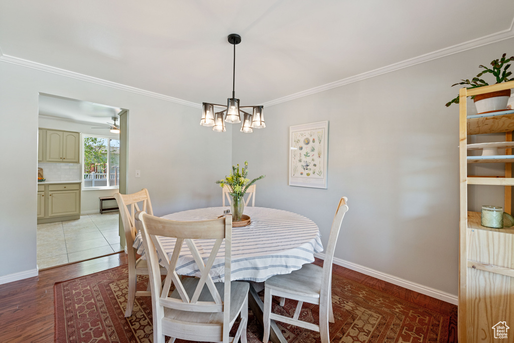 Tiled dining room with ceiling fan with notable chandelier and crown molding