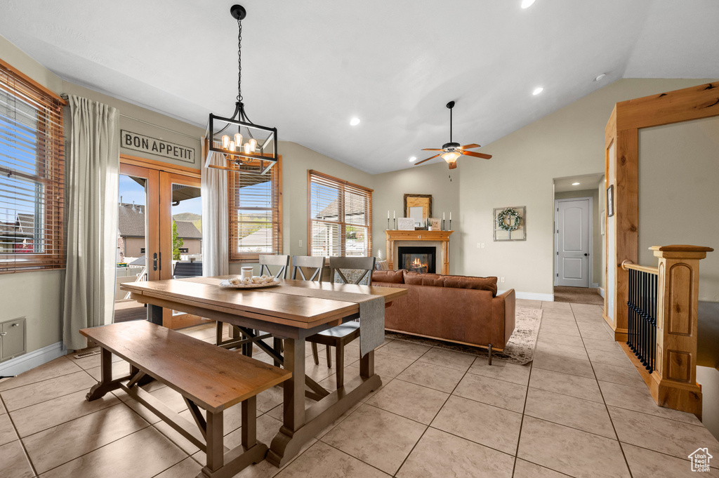 Dining area with ceiling fan with notable chandelier, vaulted ceiling, and light tile floors