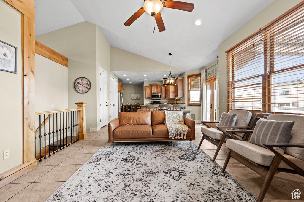 Living room featuring ceiling fan, vaulted ceiling, and light tile flooring