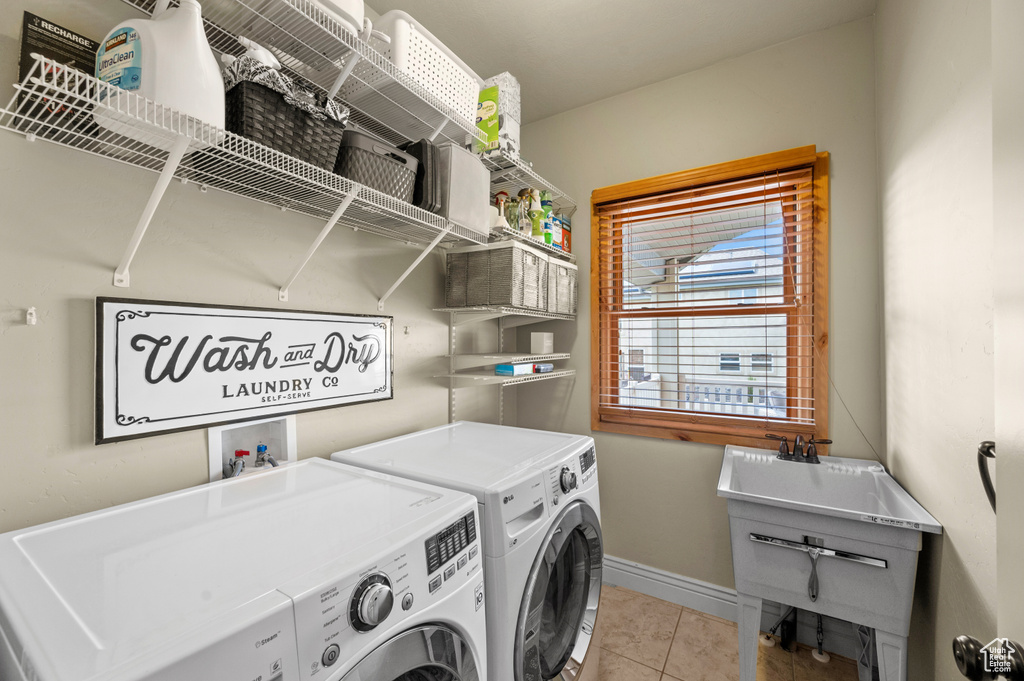 Clothes washing area featuring light tile floors, washer hookup, and washing machine and clothes dryer