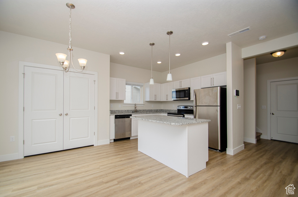 Kitchen featuring pendant lighting, stainless steel appliances, and light hardwood / wood-style floors