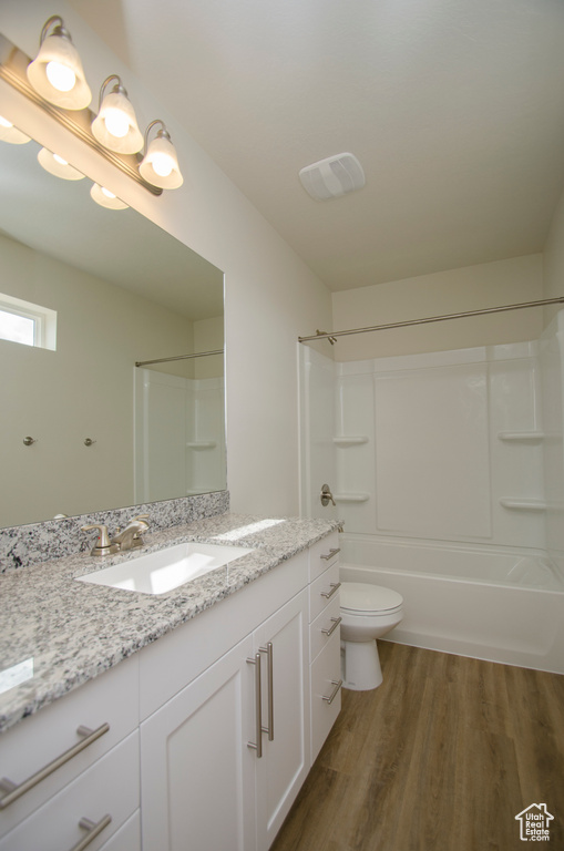 Full bathroom with wood-type flooring, vanity, toilet, and shower / washtub combination