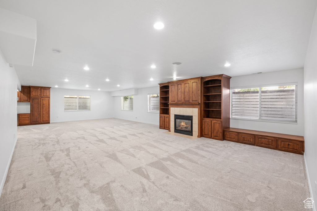 Unfurnished living room featuring light colored carpet and a tile fireplace