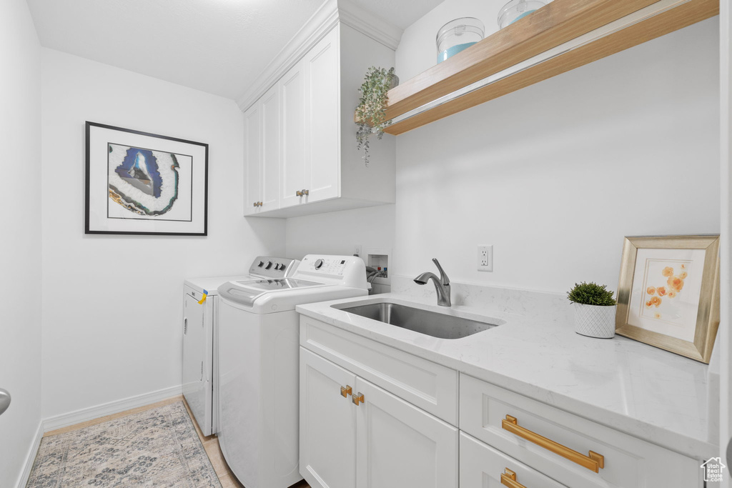 Washroom featuring cabinets, sink, washing machine and dryer, and washer hookup