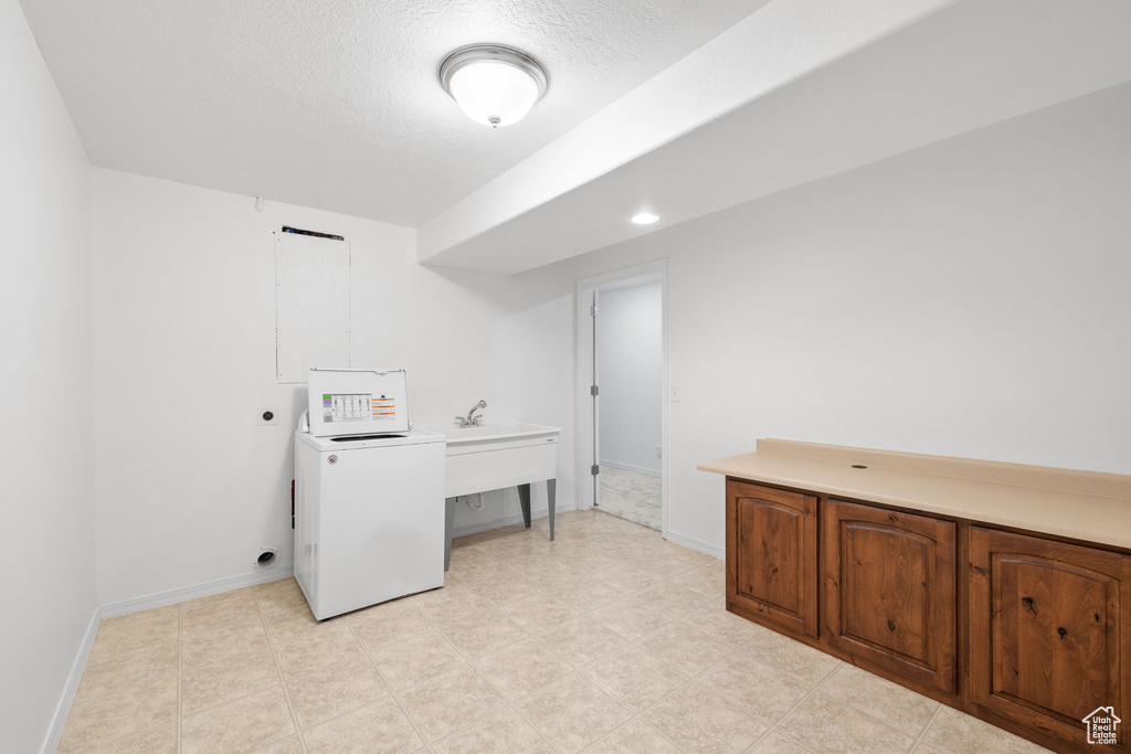 Laundry area featuring a textured ceiling, light tile floors, and washer / clothes dryer