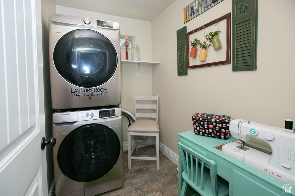 Clothes washing area with hardwood / wood-style floors and stacked washing maching and dryer