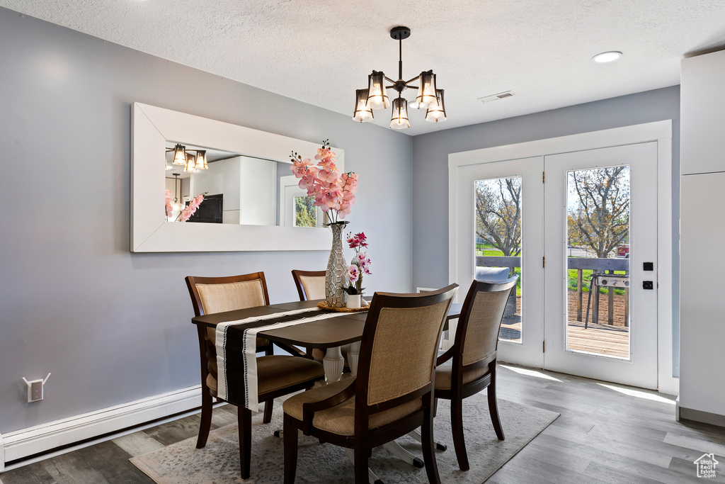 Dining room with a baseboard radiator, hardwood / wood-style flooring, a chandelier, and a textured ceiling