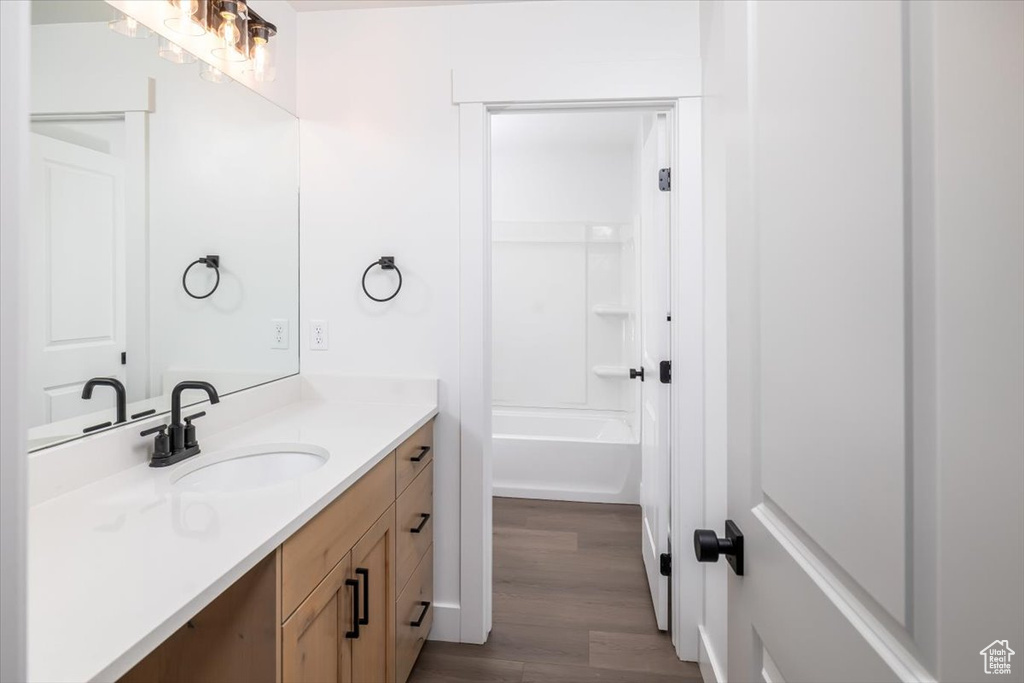 Bathroom featuring hardwood / wood-style flooring, bathtub / shower combination, and vanity with extensive cabinet space