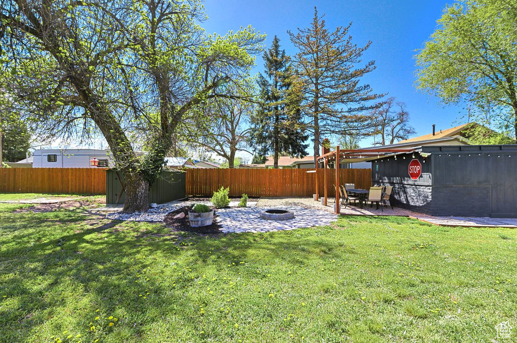 View of yard with a patio area, a fire pit, and a storage shed