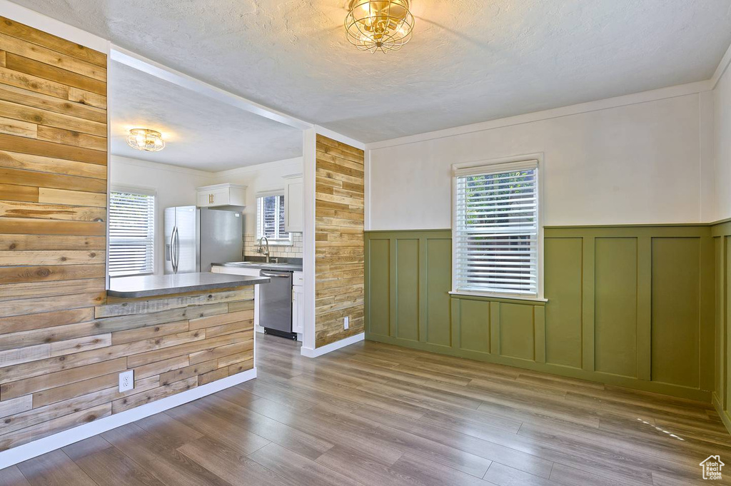 Kitchen featuring wood walls, green cabinets, hardwood / wood-style floors, appliances with stainless steel finishes, and sink