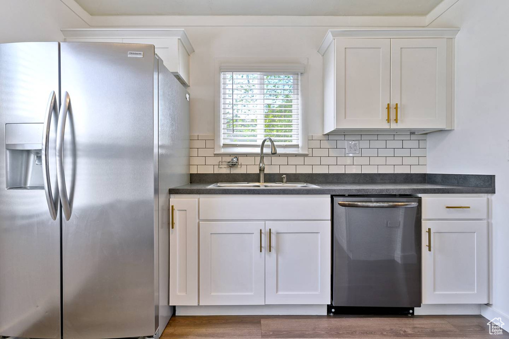 Kitchen featuring appliances with stainless steel finishes, sink, dark wood-type flooring, and tasteful backsplash