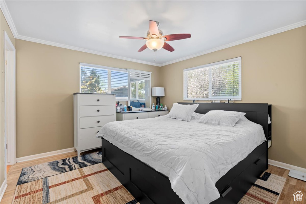 Bedroom with light hardwood / wood-style flooring, ceiling fan, and crown molding