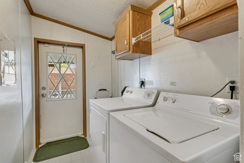 Clothes washing area with tile flooring, washer and dryer, cabinets, a textured ceiling, and electric dryer hookup