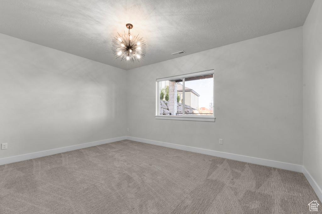 Unfurnished room with a notable chandelier and carpet floors