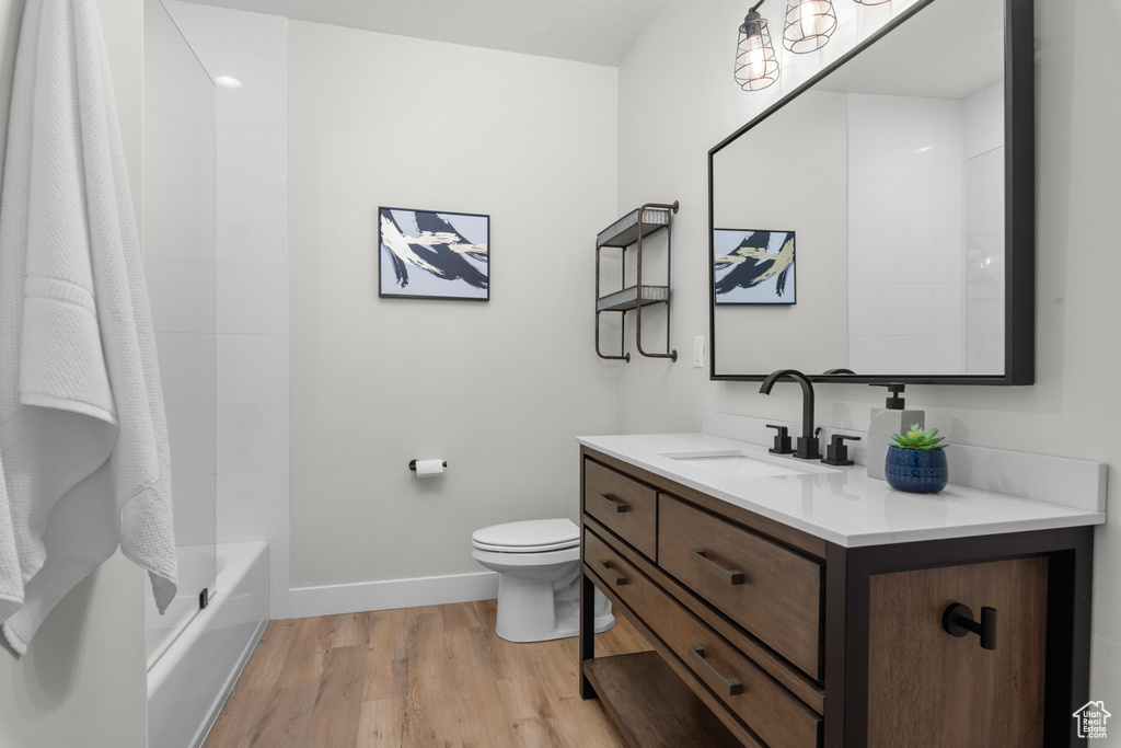 Full bathroom featuring bathtub / shower combination, oversized vanity, hardwood / wood-style floors, and toilet