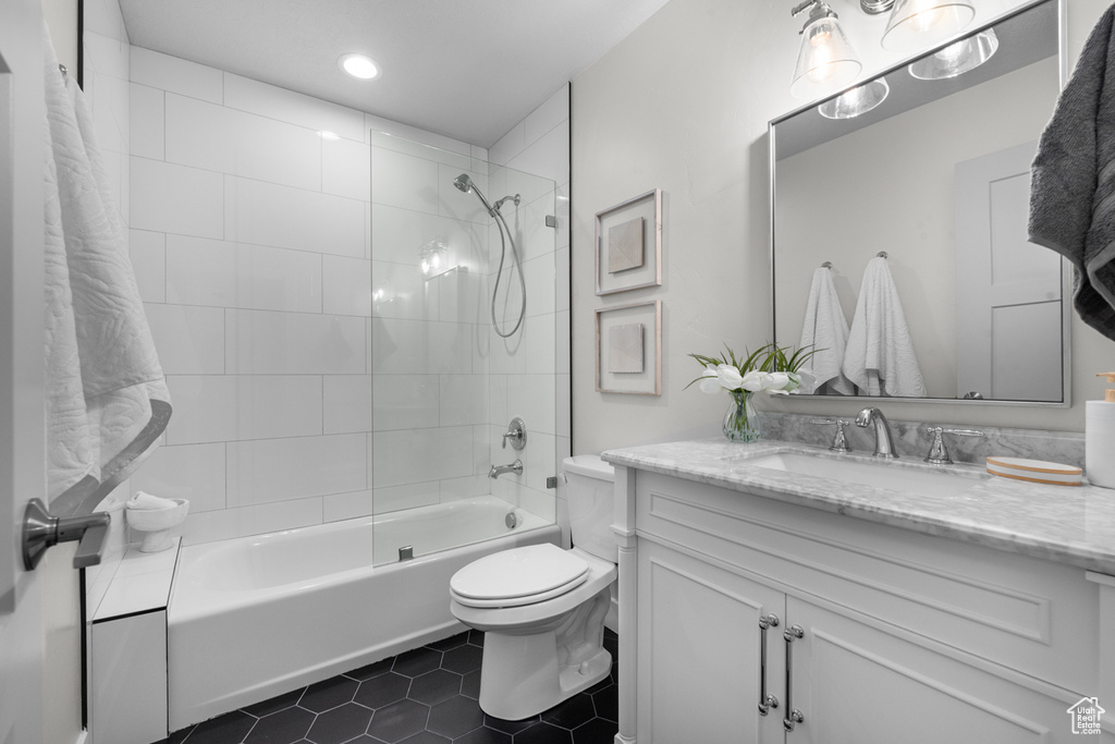 Full bathroom with tiled shower / bath combo, oversized vanity, tile floors, and toilet