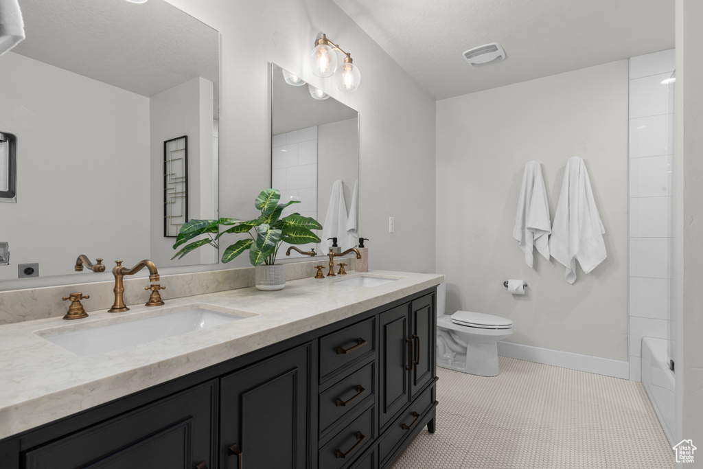 Bathroom featuring tile floors, toilet, and dual vanity