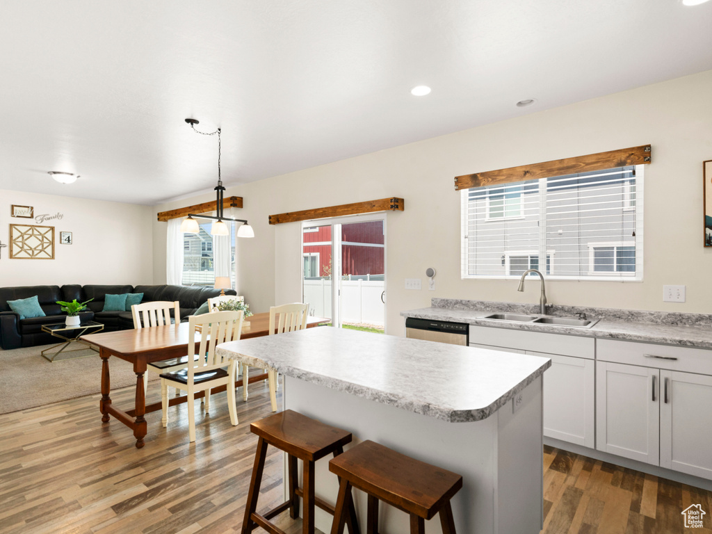 Kitchen featuring a center island, sink, dishwasher, a breakfast bar area, and light hardwood / wood-style flooring