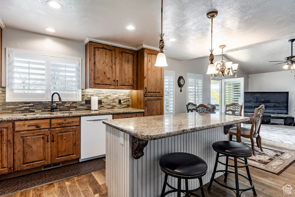Kitchen featuring a kitchen breakfast bar, pendant lighting, dark hardwood / wood-style floors, backsplash, and dishwasher