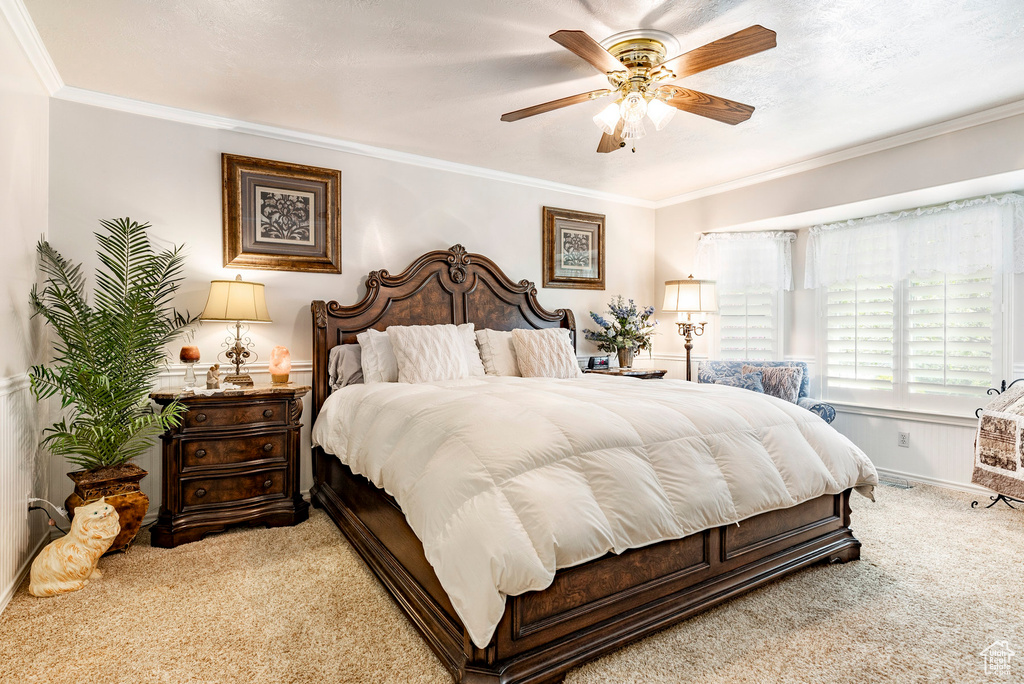 Carpeted bedroom with ceiling fan and crown molding