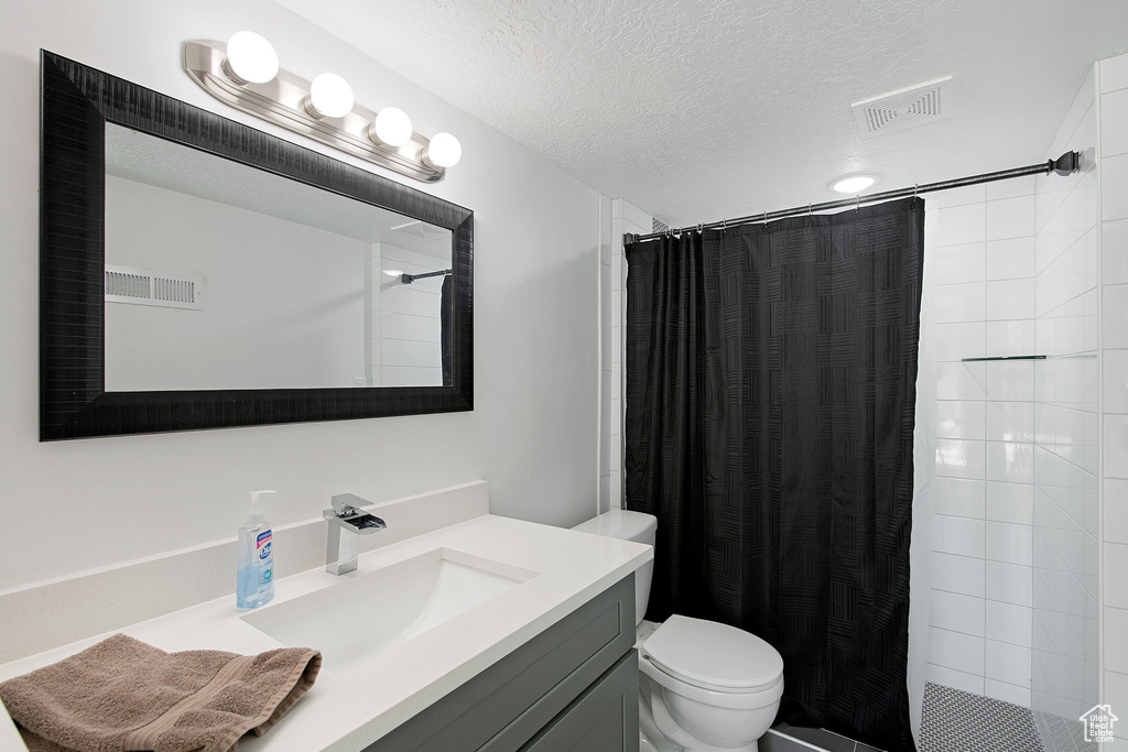 Bathroom with vanity, toilet, a shower with shower curtain, and a textured ceiling