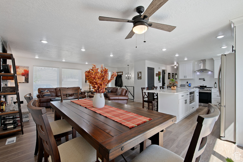 Dining space with light hardwood / wood-style flooring, ceiling fan, and a textured ceiling