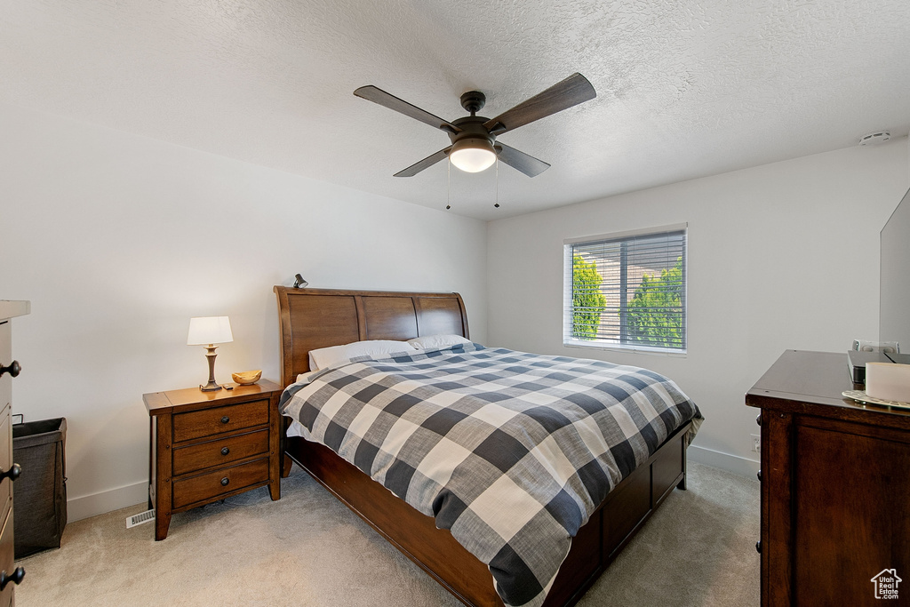 Bedroom featuring light colored carpet, ceiling fan, and a textured ceiling