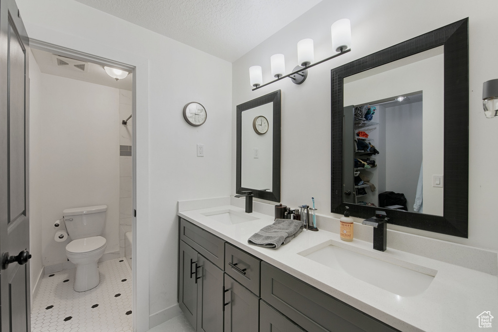 Full bathroom featuring large vanity, toilet, bathtub / shower combination, tile floors, and dual sinks