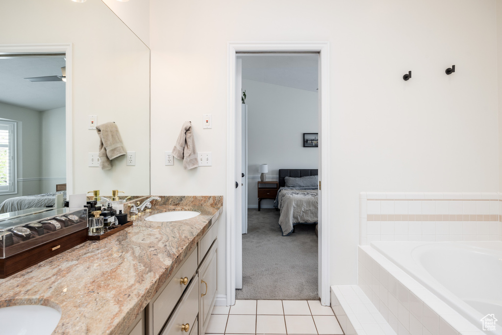 Bathroom with dual vanity, ceiling fan, tile floors, and tiled bath