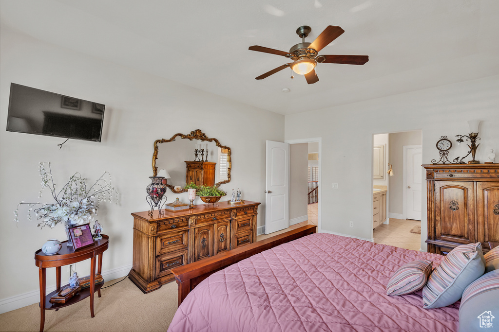 Bedroom with light colored carpet, ensuite bath, and ceiling fan
