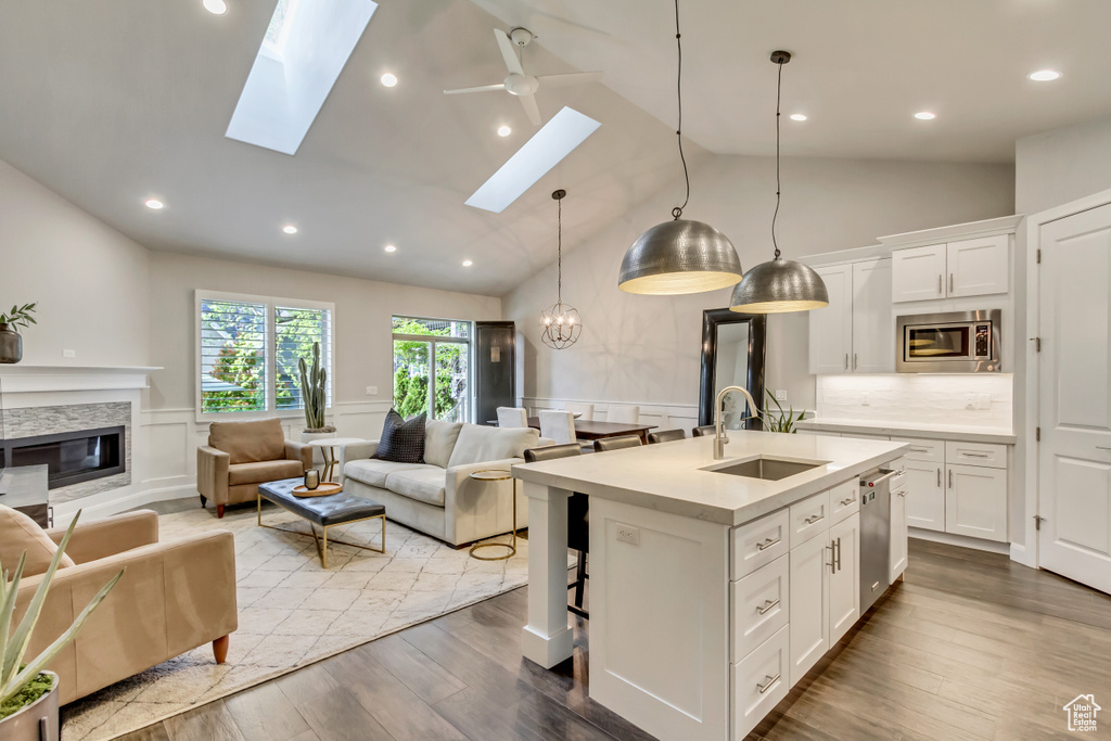 Kitchen with a skylight, a center island with sink, hardwood / wood-style flooring, and stainless steel appliances