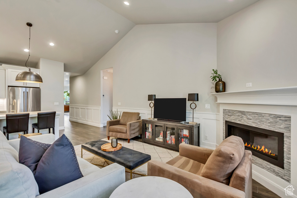 Living room featuring lofted ceiling, light hardwood / wood-style floors, and a tiled fireplace