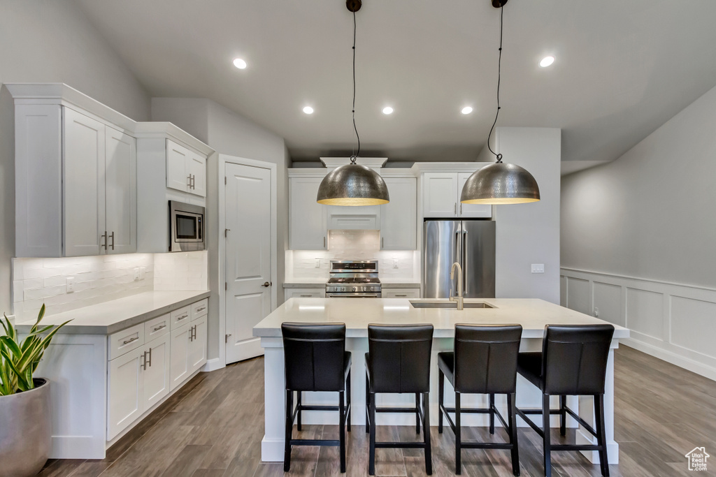 Kitchen with white cabinets, tasteful backsplash, stainless steel appliances, and dark hardwood / wood-style flooring