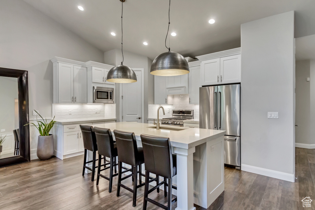 Kitchen featuring hardwood / wood-style flooring, tasteful backsplash, appliances with stainless steel finishes, and white cabinetry